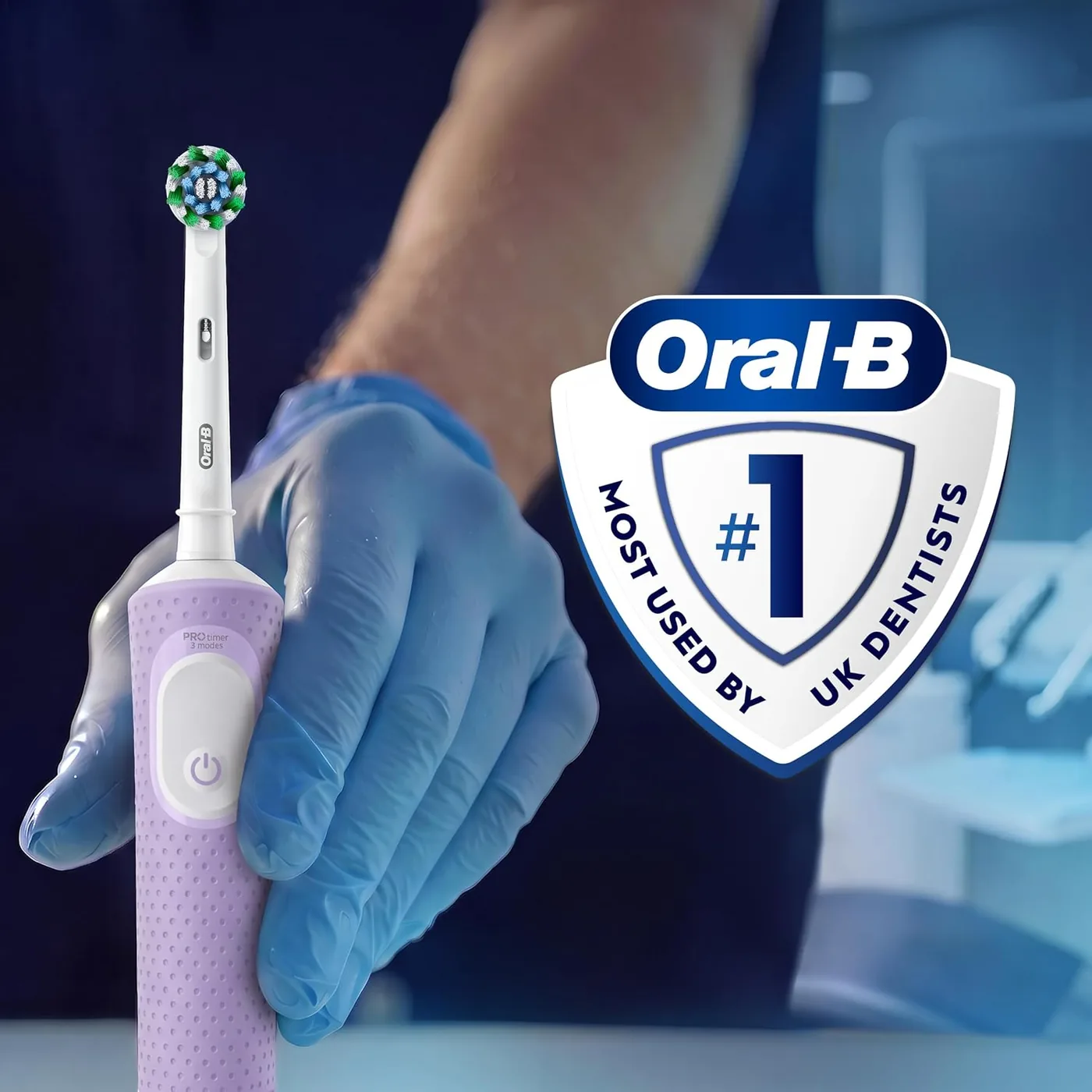 Person holding the Oral-B Vitality Pro in a gloved hand beside the Oral-B dentist badge